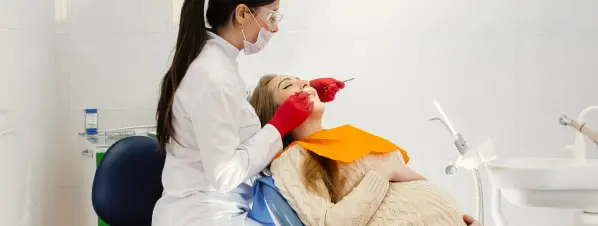 A Female Dentist Treating A Patient In Clinic
