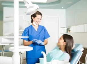 Dental Assistant Smiling And Talking To Patient