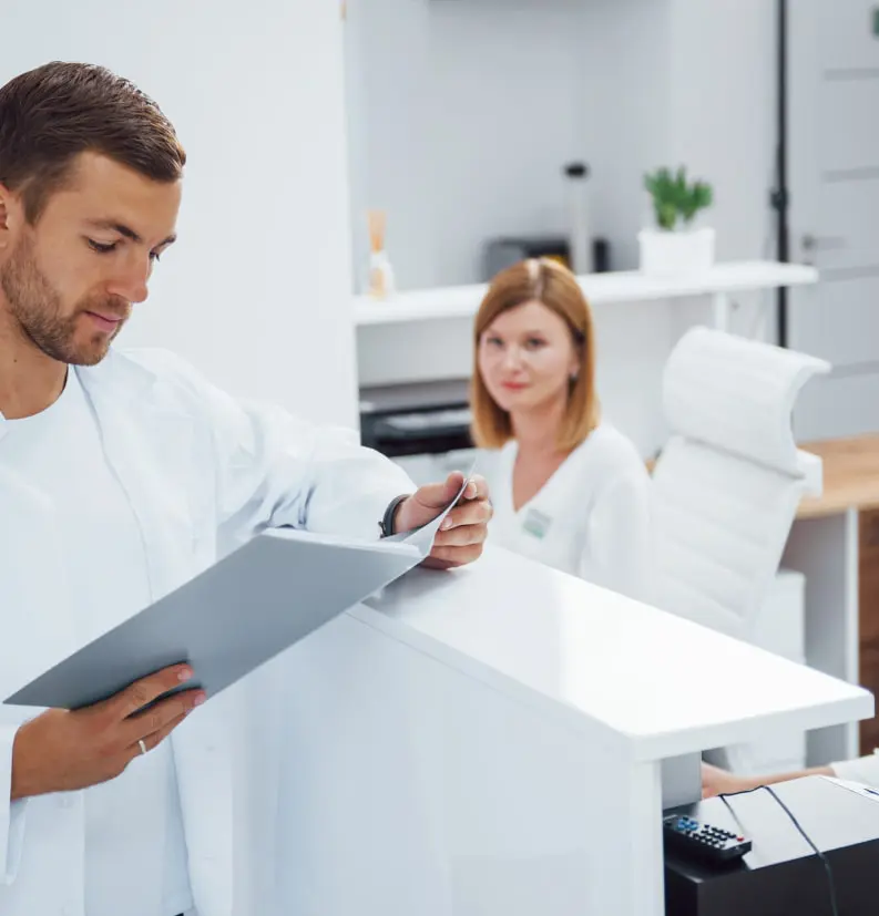 Dentist Reviewing Patient File At Reception