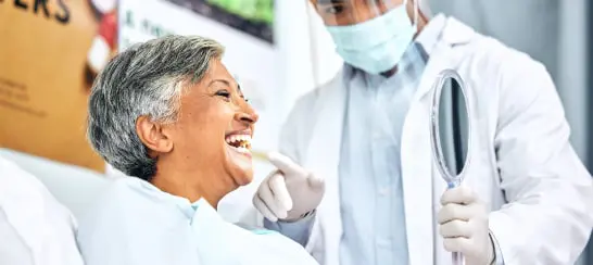 Dentist Showing Happy Senior Patient Their Smile In Mirror After Treatment